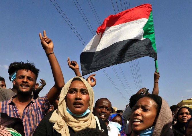 Sudanese protesters flash victory signs and lift national flags as they demonstrate in the capital Khartoum to denounce overnight detentions by the military. (AFP)