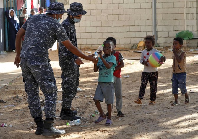 In this file photo taken on October 11, 2021 Libyan security forces hand water to children as African migrants gather at a makeshift shelter in the capital Tripoli’s suburb of Ain Zara. (AFP)