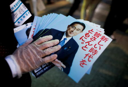 An election campaign staff member holds leaflets of Japan's ruling Liberal Democratic Party with cover photos of Japan's Prime Minister and the party's president Fumio Kishida, as he distributes these to voters during an election campaign on the first day of campaigning for the upcoming lower house election in Tokyo, Japan, October 19, 2021. (Reuters)