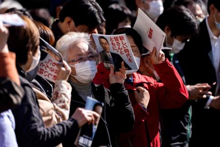 Supporters of Japan's Liberal Democratic Party (LDP) hold leaflets of Prime Minister Fumio Kishida as they wait for the start of an election campaign in Saitama on October 30, 2021, a day before the general elections. (AFP)