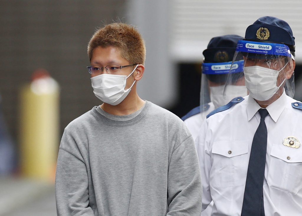 Kyota Hattori (L), suspect in a Halloween stabbing and fire attack on a train that left 18 people hospitalised, is escorted to the prosecutor's office from the Chofu police station in Tokyo on November 2, 2021. (AFP)