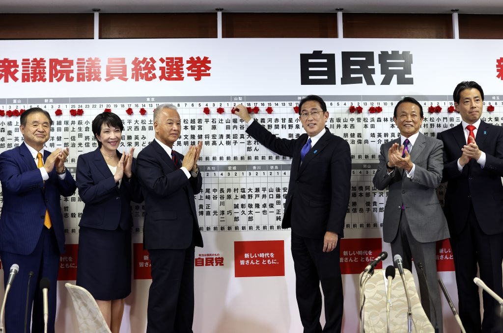 Japan's Prime Minister and ruling Liberal Democratic Party leader Fumio Kishida, third from right, poses with key party members as he puts rosettes by successful general election candidates' names on a board at the party headquarters in Tokyo, Oct. 31, 2021. (File photo/AP) 
