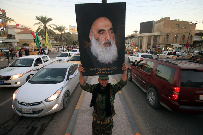 A member of the Hashed Al-Shaabi (Popular Moblization units) carries a portrait of Iraqi Shiite cleric Grand Ayatollah Ali Al-Sistani in a street in the southern city of Basra. (AFP/File Photo)