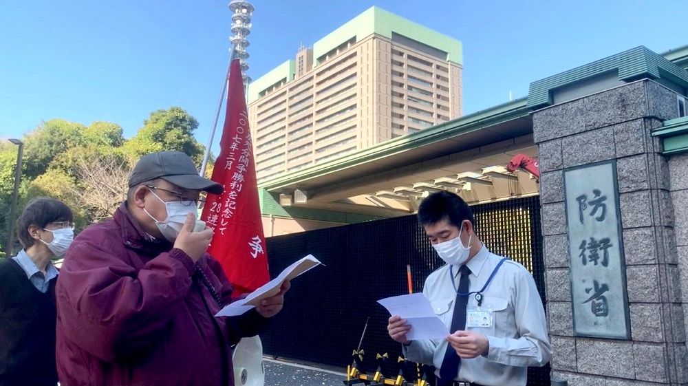 A protester reads a letter addressed to Japan’s defense minister at the ministry’s building entrance on November 14, demanding the removal of missiles from the far southern islands. (ANJ/ Pierre Boutier)