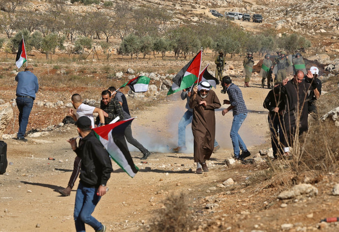 Palestinian protesters run from tear gas fired by Israeli security forces, during a demonstration against the establishment of Israeli outposts on Palestinian lands, in Beit Dajan, east of Nablus in the occupied West Bank, on November 12, 2021. (AFP)