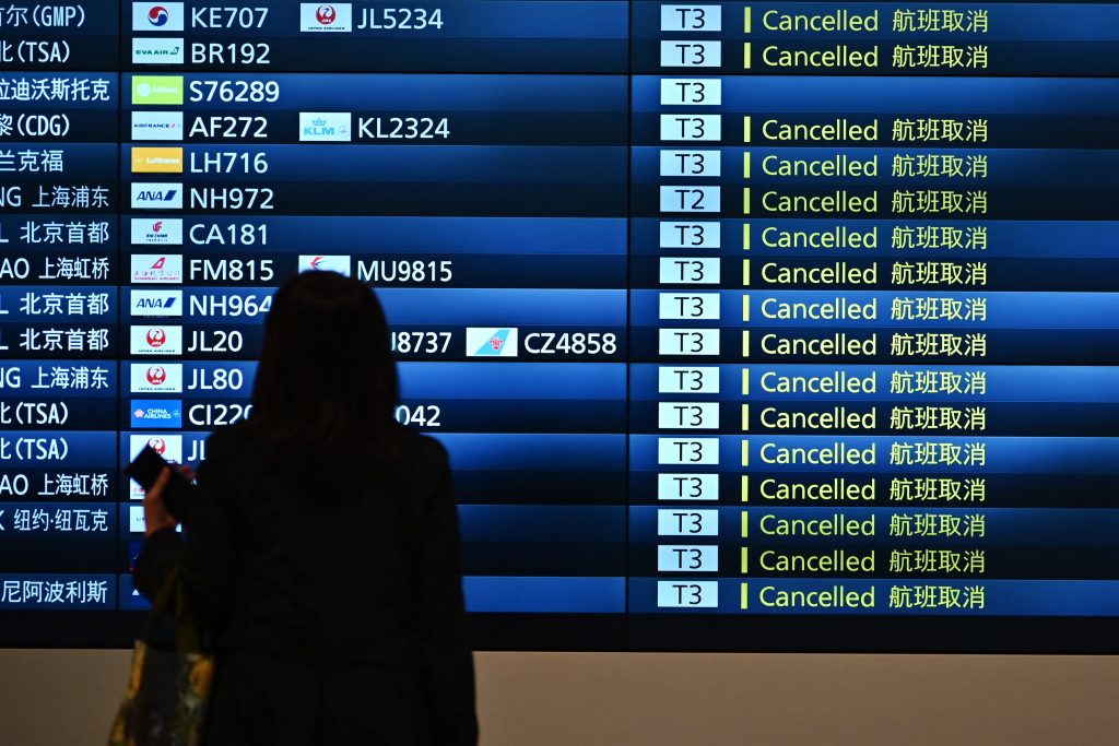 A woman looks at a signboard displaying cancelled flights at an arrivals floor of the international terminal at Haneda airport in Tokyo. (AFP)