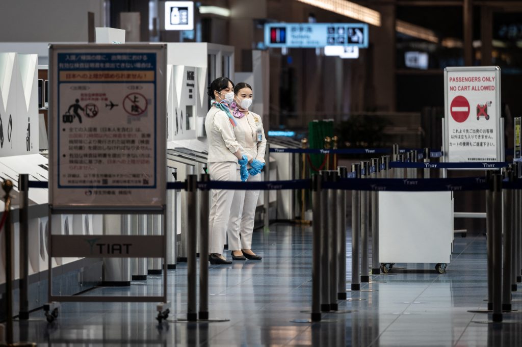 Staff members stand at the departure gate of Tokyo's Haneda international airport as Japan announced plans to bar all new foreign travellers over the Omicron variant of Covid-19. (AFP)