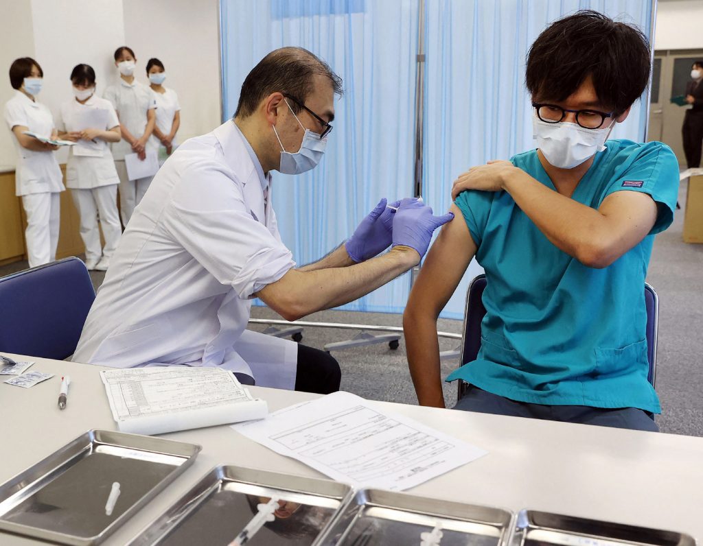 A man (R) receives a third dose of the Pfizer vaccine against the COVID-19 coronavirus at the Tokyo Medical Center in Tokyo on December 1, 2021, as part of an inoculation campaign for health care workers. (AFP)