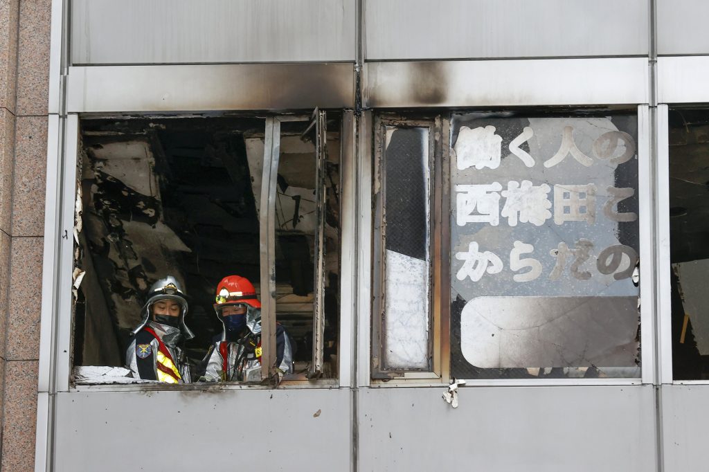 Firefighters stand on a floor at a building where a fire broke out in Osaka, western Japan, Dec. 17, 2021. (File photo/Kyodo News via AP)