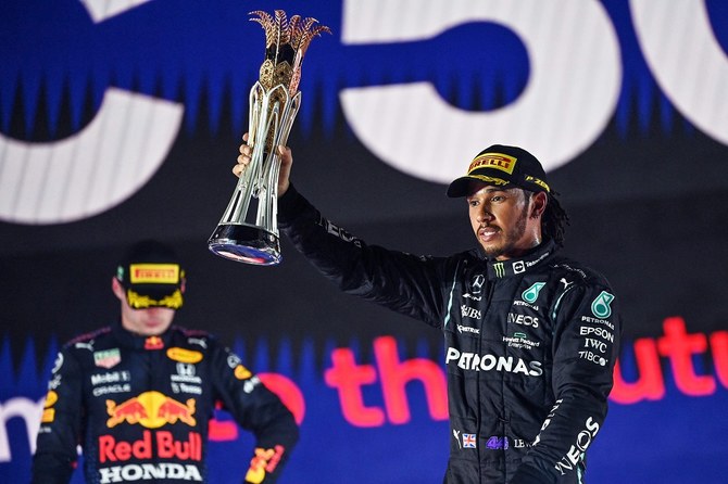 Winner Mercedes' British driver Lewis Hamilton (R) reacts with his trophy flanked by second-placed Red Bull's Dutch driver Max Verstappen (L) on the Jeddah podium. (AFP)