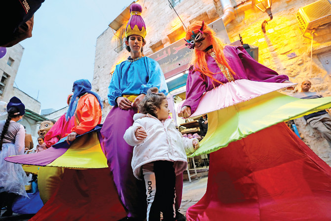 A child stands next to Palestinians dressed in various costumes during a celebration in Bethlehem in the Israeli-occupied West Bank. (Reuters)