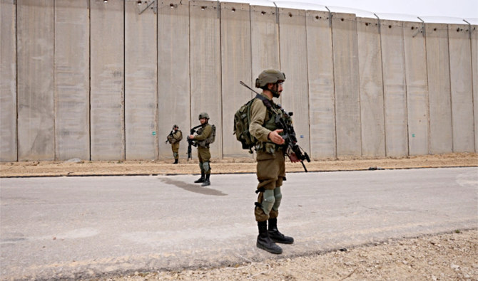Israeli soldiers stand on guard by the fence along the Gaza Strip near Moshav Netiv HaAsara in southern Israel. (AFP)