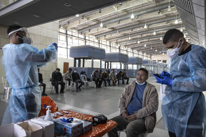 Medics from Magen David Adom, Israel’s national emergency service, conduct COVID-19 tests on Palestinians entering Israel from the Gaza Strip at the Erez Crossing, on the Israel-Gaza border, on Thursday. (AP)