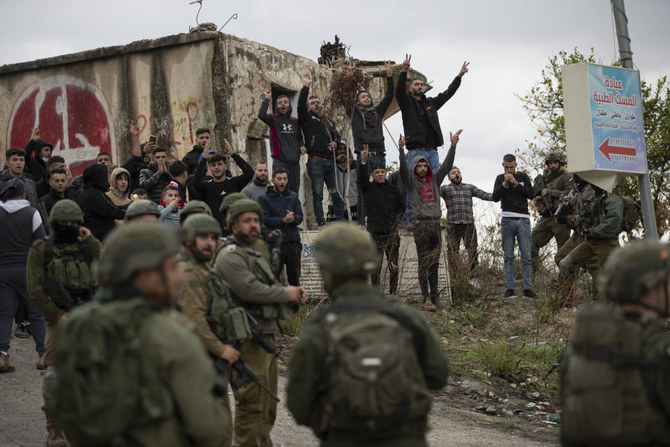 Israeli soldiers stand between Palestinians and Jewish settlers following a settler attack on the West Bank village of Burqa, Friday, Dec. 17, 2021. (AP Photo)