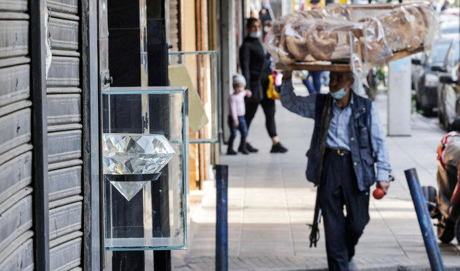 A pastry pedlar walks past closed jewellers' shops in the popular market of the Burj Hammoud neighbourhood of Lebanon's capital Beirut on December 14, 2021. (AFP)