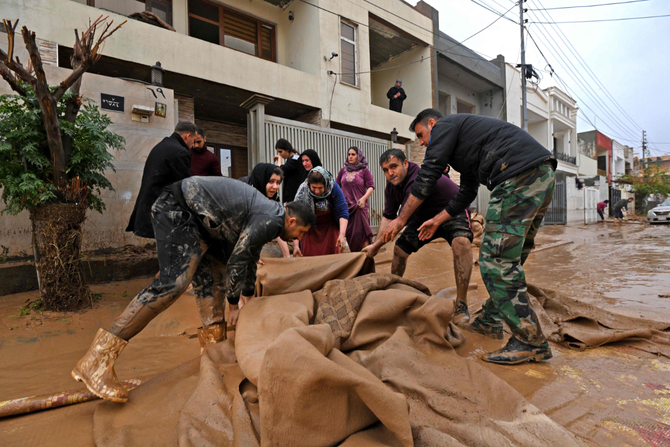 Residents clear debris in Daratu, on the outskirts of Irbil on Dec. 17, 2021, after flash floods caused by torrential rains left 12 people dead. (Photo by AFP)