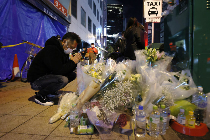 A mourner prays in front of offerings near a building where a fire broke out, in Osaka, western Japan Saturday, Dec. 18, 2021. (AP)