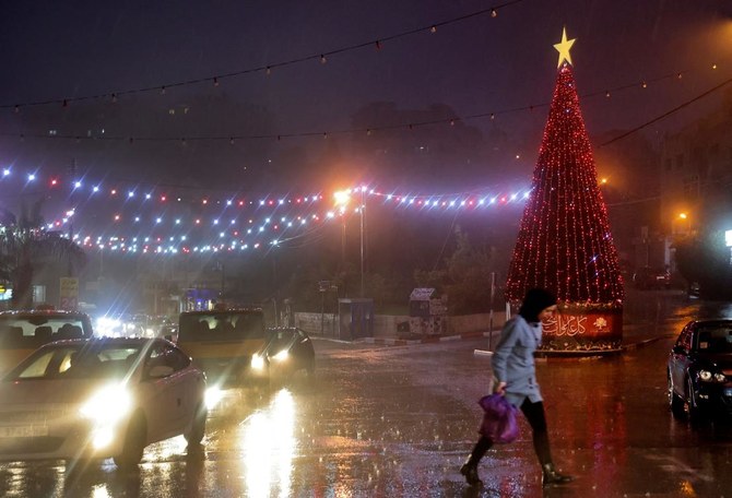 A Palestinian woman crosses a road during rain in the West Bank on Monday. (AFP)
