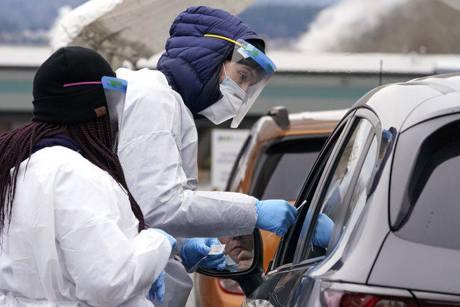 COVID-19 testing specialists test a driver at a drive-up testing location on Dec. 21, 2021, in Bellingham, Washington. (AP Photo/Elaine Thompson)