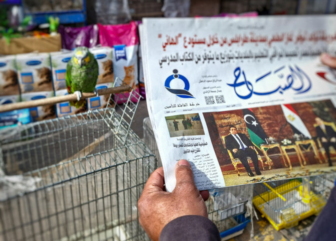 A man reads a newspaper in the Libyan capital Tripoli, on Dec. 23, 2021, with an article on its front page about the postponement of the country's elections. (Photo by Mahmud Turkia / AFP)