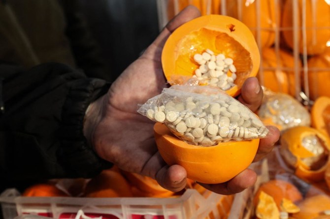 A man shows fake oranges filled with Captagon pills and dissimulated in boxes containing real fruit, after the shipment was intercepted at the Beirut port on December 29, 2021. (AFP)