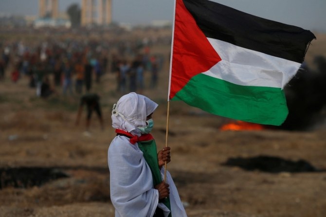 A woman holds a Palestinian flag during a protest at the Israel-Gaza border fence, Gaza Strip, Oct. 19, 2018. (Reuters)