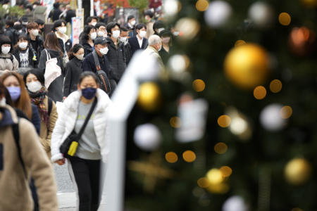 People wearing face masks walk near a Christmas tree along a pedestrian crossing at Shibuya district Friday, Dec. 17, 2021, in Tokyo. (AP)