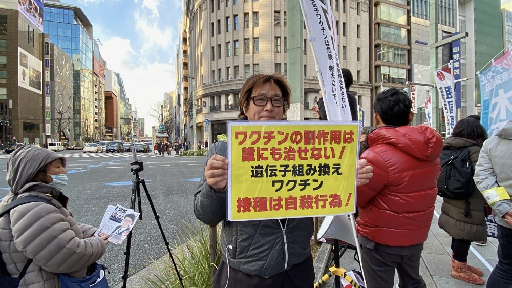 A demonstrator holds a placard that claims, “No one can cure the side-effects of the vaccine! Taking genetically modified vaccination is suicidal!” (ANJ) 