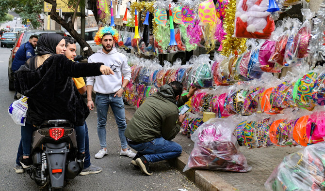 A woman riding a motorcycle points at party hats and accessaries sold by a street vendor, ahead of the New Year's Eve celebrations in the Lebanese capital Beirut, on December 31, 2021. (AFP)