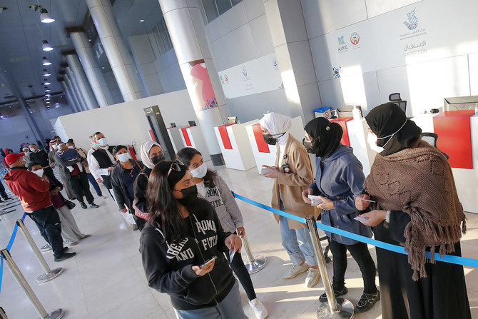 People are directed towards vaccination booths as they arrive to receive COVID-19 coronavirus vaccine booster doses at the vaccination centre at the Kuwait International Fairground in Kuwait City on Jan. 3, 2022. (AFP)