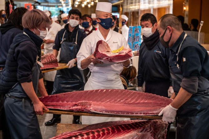 Chef Akifumi Sakagami, center, holds a part of a tuna which was bought jointly by Michelin-starred sushi restaurant operator Onodera Group and wholesaler Yamayuki for $145,290 at the Toyosu fish market’s New Year auction. (AFP)