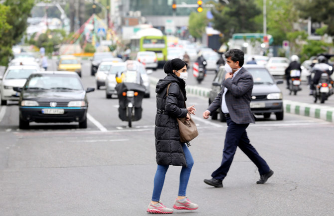 Iranians cross a main road in Tehran, where dissident poet and filmmaker Baktash Abtin died on Saturday in detention after falling ill with Covid-19. (AFP)