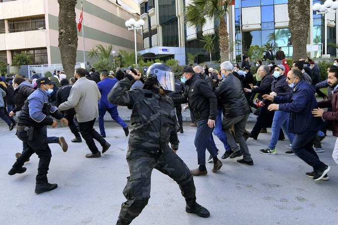 Tunisian demonstrators run for cover during clashes with police as they protest against President Kais Saied, on the 11th anniversary of the Tunisian revolution in the capital Tunis. (AFP)