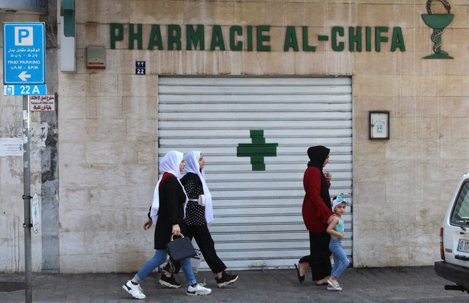 Residents pass by a shuttered pharmacy in Beirut during a nationwide strike on July 9, 2021. (AFP file photo)