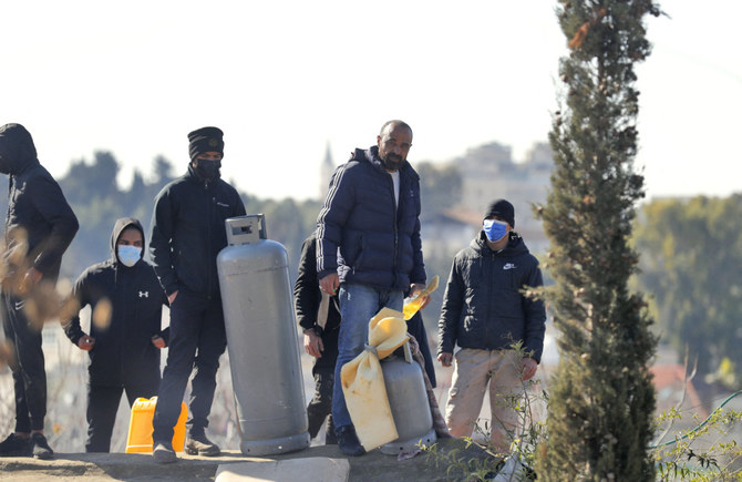 Palestinian men hold a gas tank on the roof of a house as Israeli police prepare to evict a family from the same building on Jan. 17, 2022 in Sheikh Jarrah. (Ahmad Gharabli / AFP)
