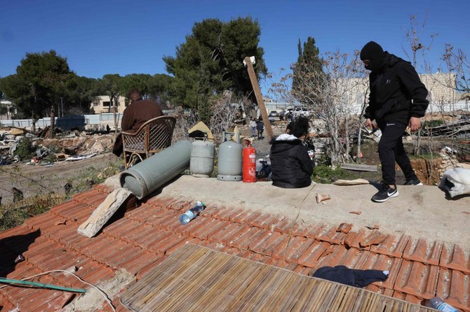 Members of the Palestinian Salhiya family sit on the roof of their home as they protest their eviction by Israeli Police and the Jerusalem municipality, on January 18, 2022 in Jerusalem's east district of Sheikh Jarrah. (AFP)