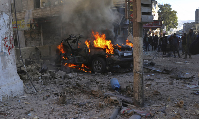 Syrians around a burning car hit by a shell, in the town of Afrin, north of Aleppo, Thursday, Jan. 20, 2022. (AP)