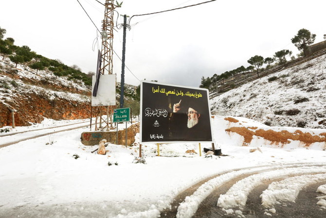 A poster depicting Lebanon's Hezbollah leader Sayyed Hassan Nasrallah is seen next to snow covered trees in Zillaya, Lebanon January 19, 2022. (Reuters)