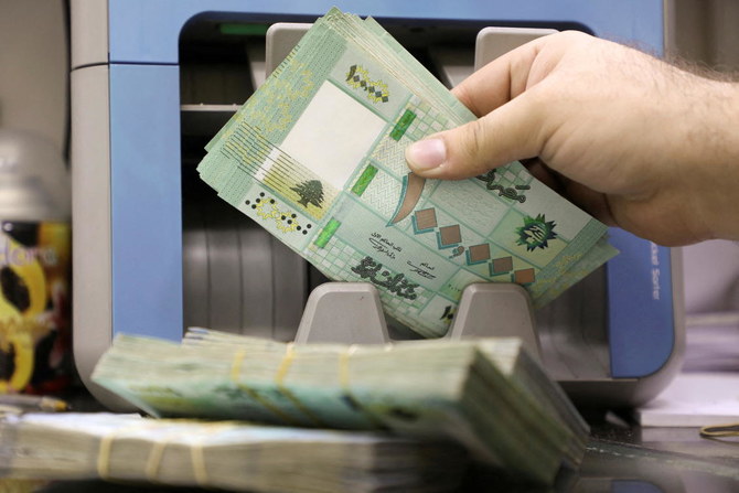 A man counts Lebanese pound banknotes at a currency exchange shop in Beirut on January 5, 2022. (Reuters)