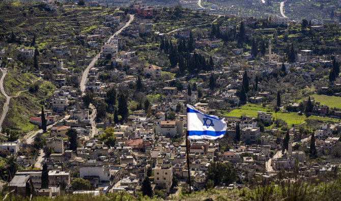 The Palestinian village of Burqa is seen as an Israeli flag is placed in the Jewish West Bank outpost of Homesh, Monday, Jan. 17, 2022. (AP)