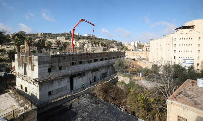 Builders work on new constructions in a settlement zone in the Israeli-controlled Al-Shuhada street, in the old town of the flashpoint Palestinian city of Hebron in the occupied West Bank, on January 3, 2022. (AFP)