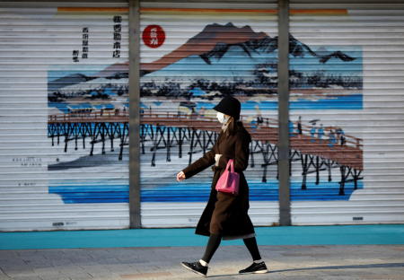 A woman wearing a protective face mask, amid the coronavirus disease (COVID-19) outbreak, makes her way at a business district on the first business day of the New Year in Tokyo, Japan, January 4, 2022. (Reuters)