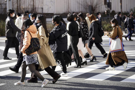 People wearing protective masks to help curb the spread of the coronavirus walk at a pedestrian crossing Thursday, Jan. 13, 2022, in Tokyo. (AP)