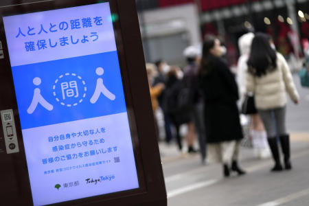 People walk past a public awareness sign for social distancing to help reduce the spread of the coronavirus Friday, Jan. 28, 2022, in Tokyo. (AP)