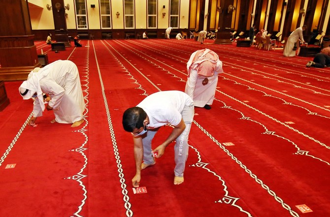 Kuwaiti worshippers remove social distancing stickers from inside a mosque in Kuwait City on October 21, 2021, a day before the ending of social distancing at mosques. (File/AFP)