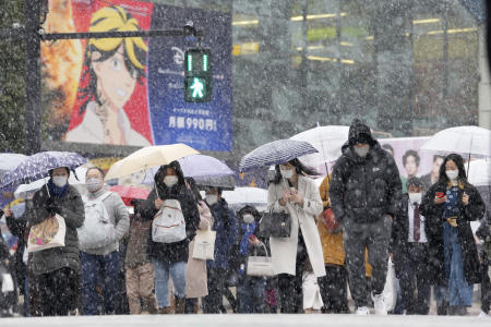 People walk across at the famed Shibuya scramble crossing as the snow comes down Thursday, Jan. 6, 2022, in Tokyo. (AP)