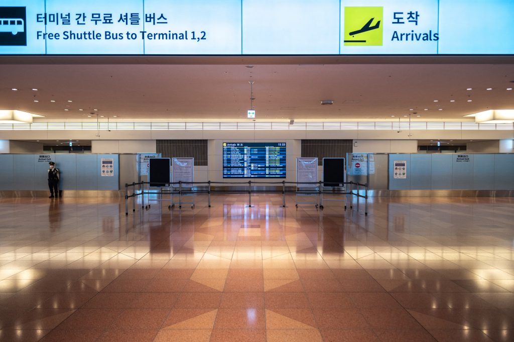A police officer (L) stands guard in an empty arrival hall at Tokyo's Haneda international airport. (AFP)