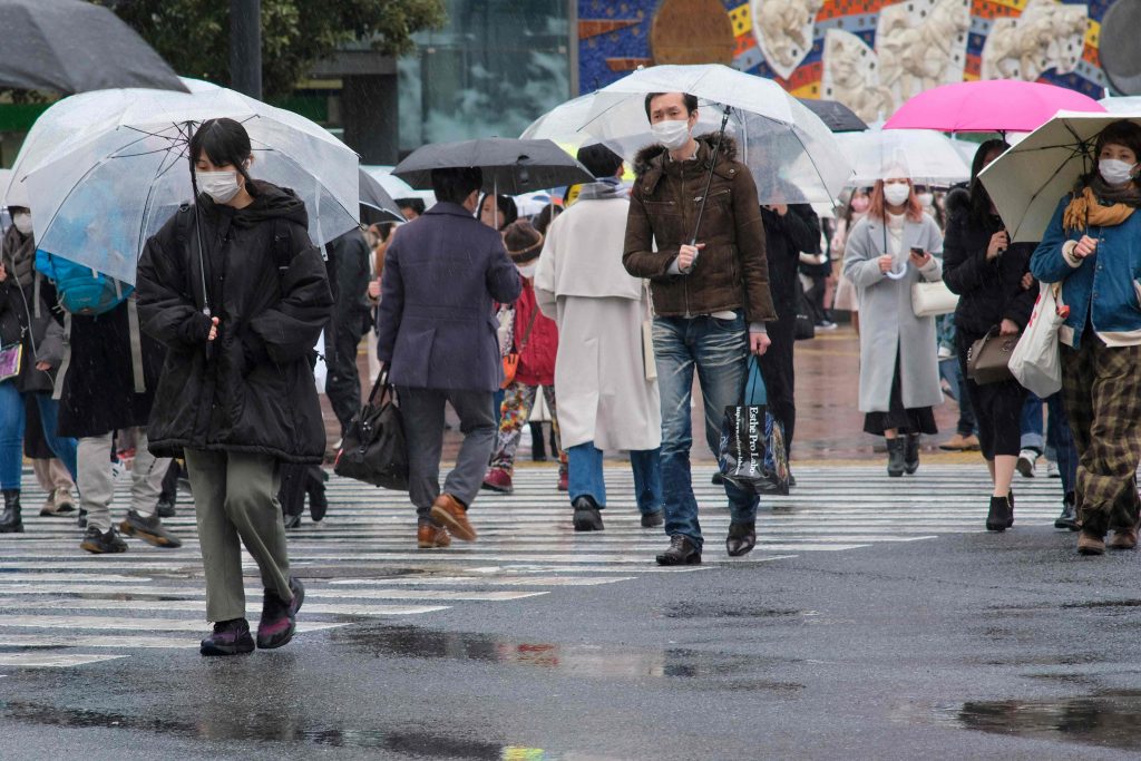 People walk at Shibuya crossing in rainy Tokyo on February 13, 2022 amid the coronavirus pandemic. (AFP)