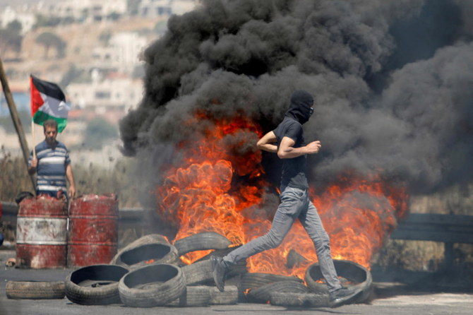 FILE PHOTO: A Palestinian demonstrator runs past burning tires during a protest over tension in Jerusalem and Israel-Gaza escalation, near Nablus in the West Bank in May 2021. (Reuters)