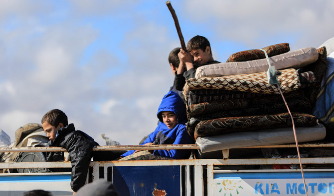 Internally displaced Syrians sit atop their belongings in the back of a truck at a camp, before being transported to a new housing complex in the opposition-held area of Bizaah, northern Aleppo governorate (AFP/File)